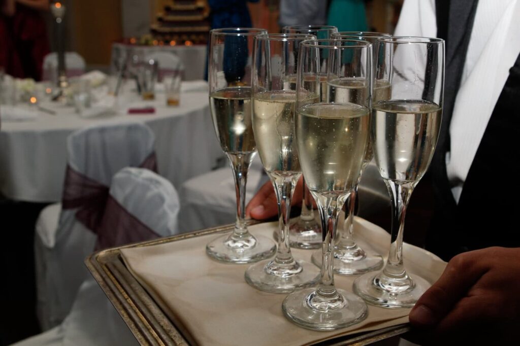 close up of champagne glasses on a platter carried by a waiter