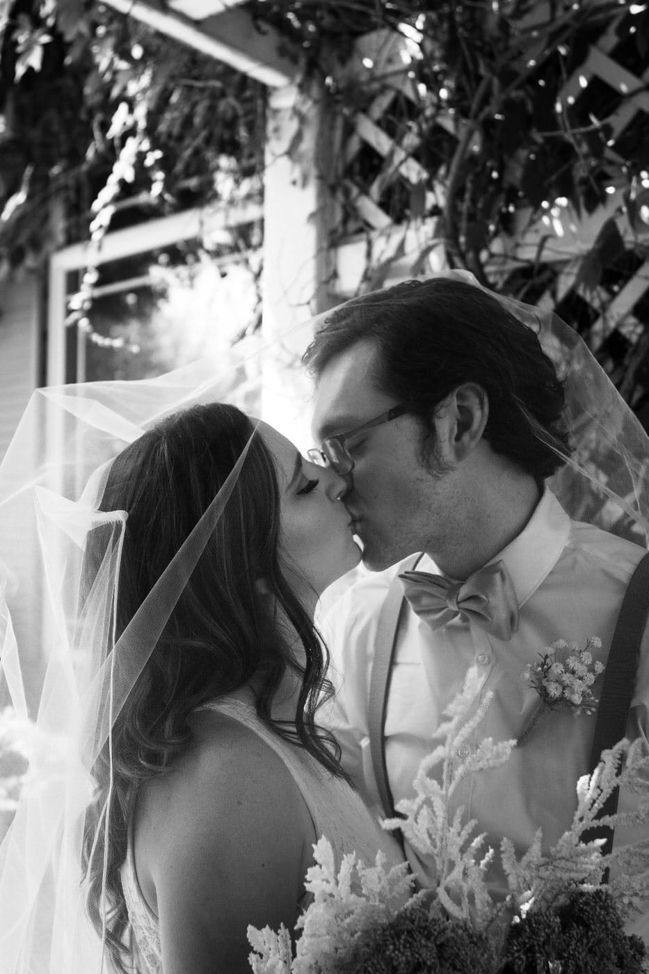 bride and groom embrace with bride's veil draped over their heads