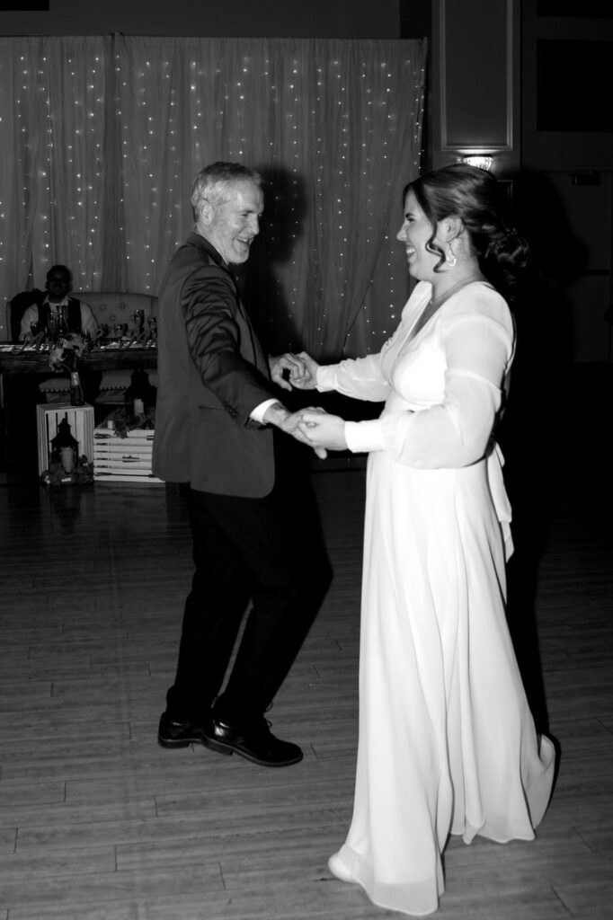 father and daughter dance smiling at wedding reception