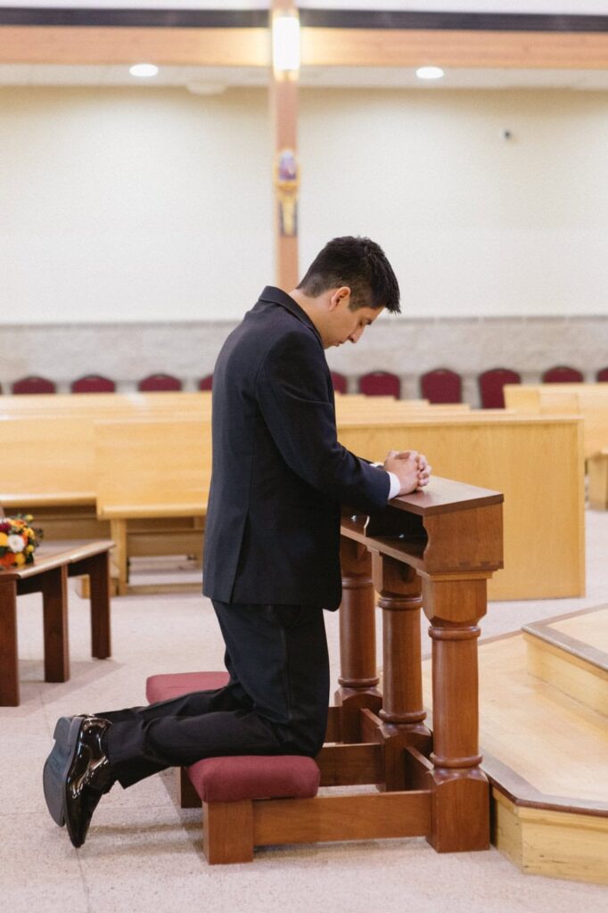 groom kneeling and praying before wedding