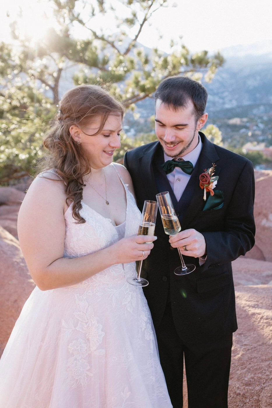 A bride and groom clink champagne glasses at garden of the gods park in colorado springs.